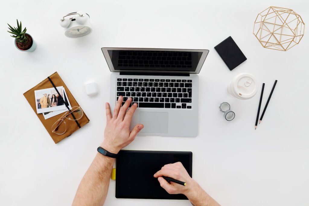 person using macbook pro on white table